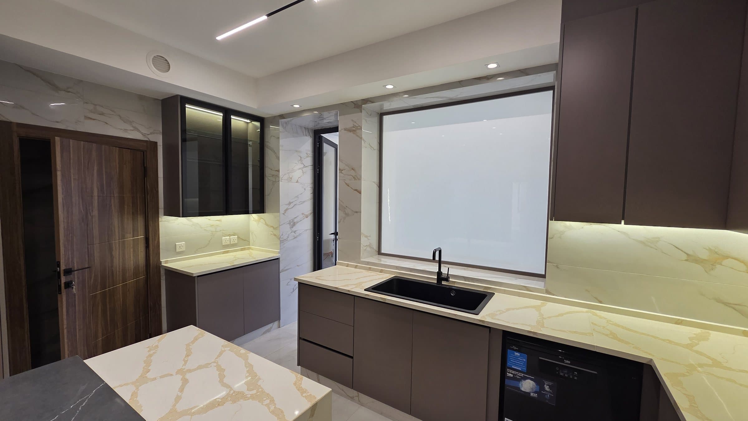 Residence 102 — Kitchen from central showing the maid door and washing area door on left and the private glass window that dims leading to living room