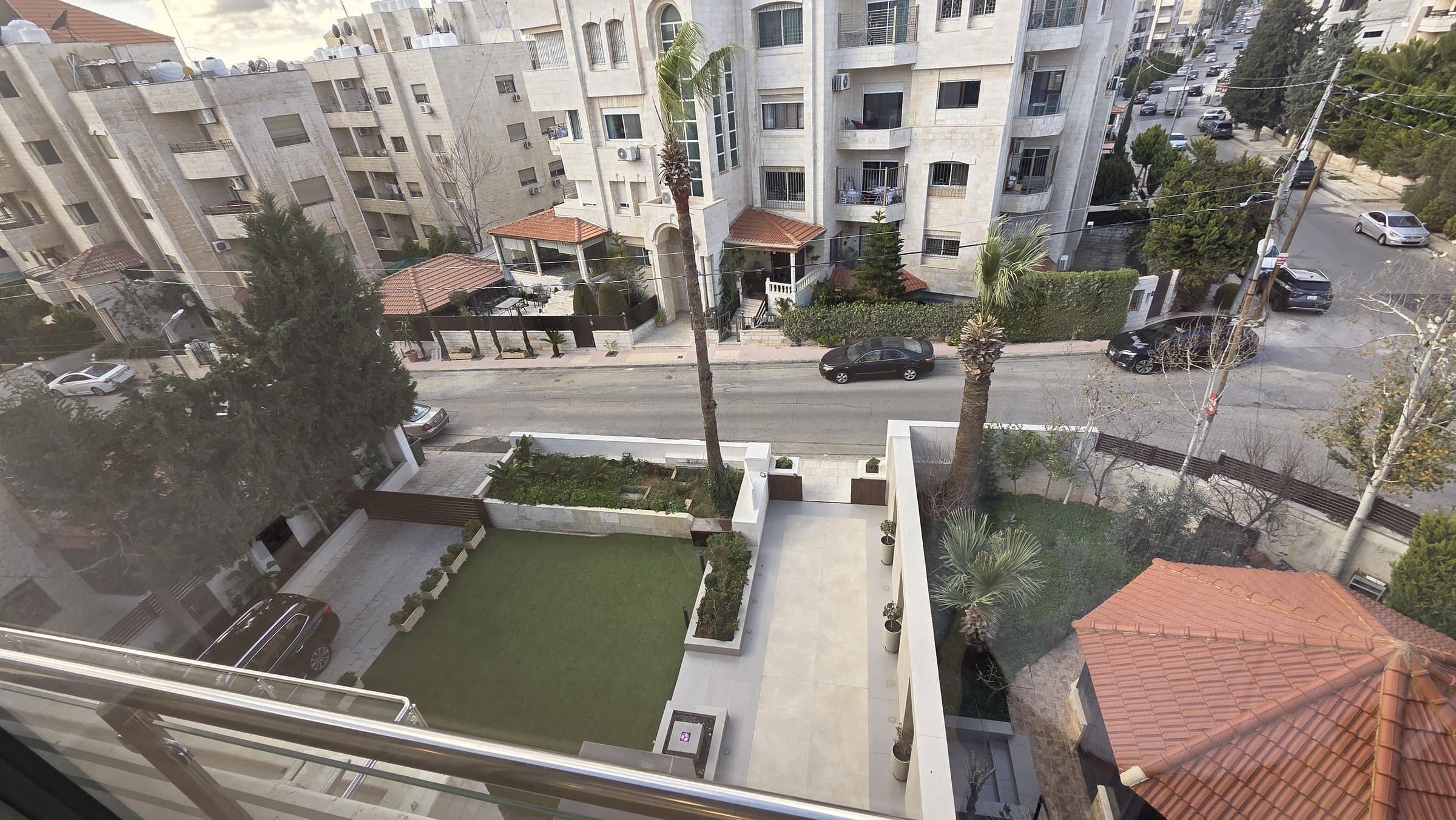 View from a Residence 201 terrace over the building's landscaped garden and green lawn to the wide, open residential street beyond