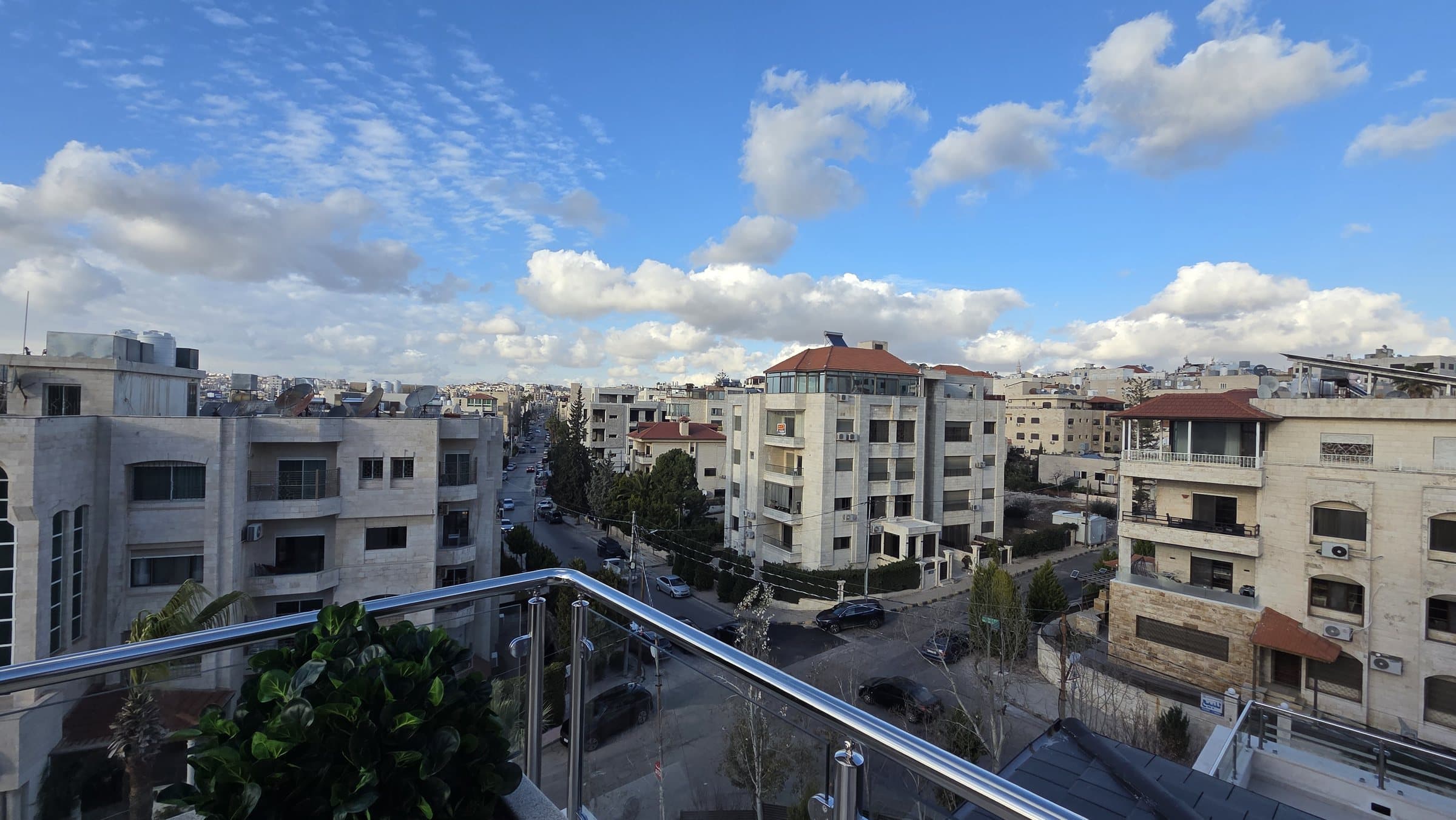 Open panoramic view from a rooftop terrace over Um Uthaina under open sky, with no adjacent building blocking the horizon