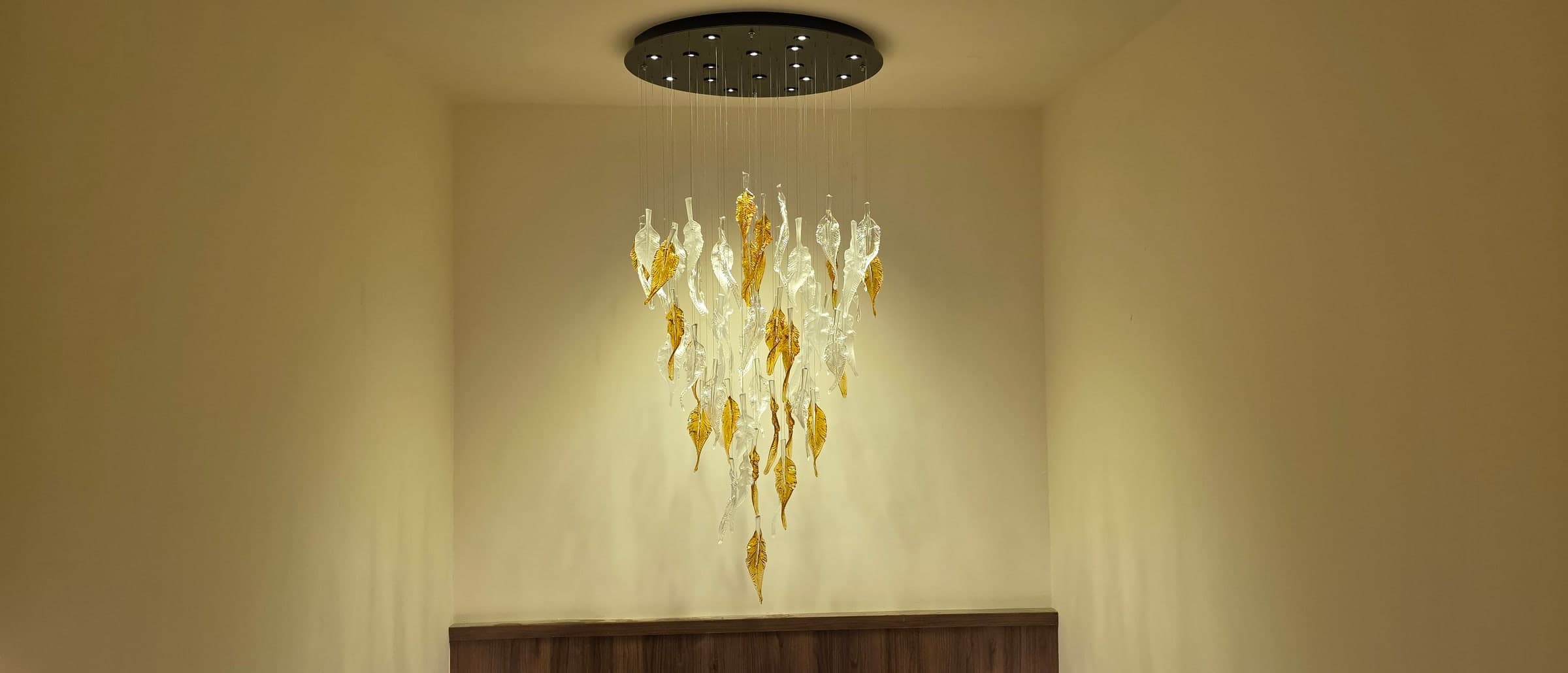 Chandelier of cascading clear, white, and amber glass leaves on the rooftop landing