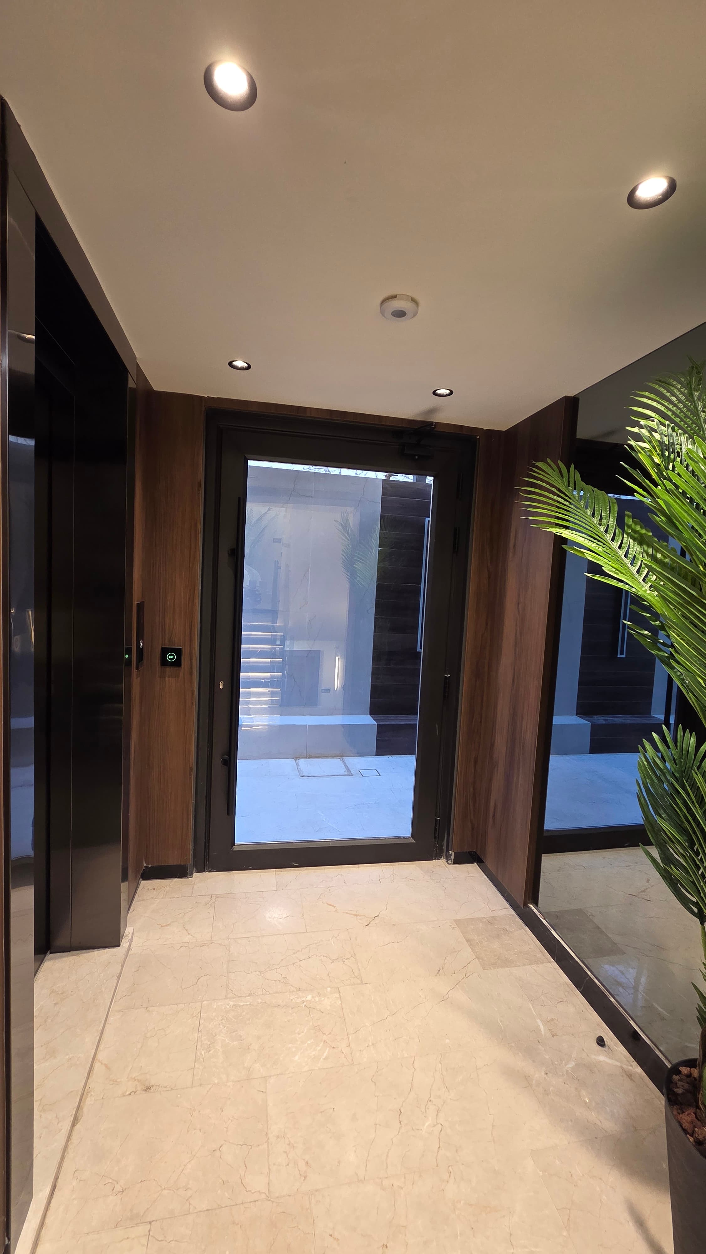 Ground floor lobby with walnut walls, glass entrance door, and elevator