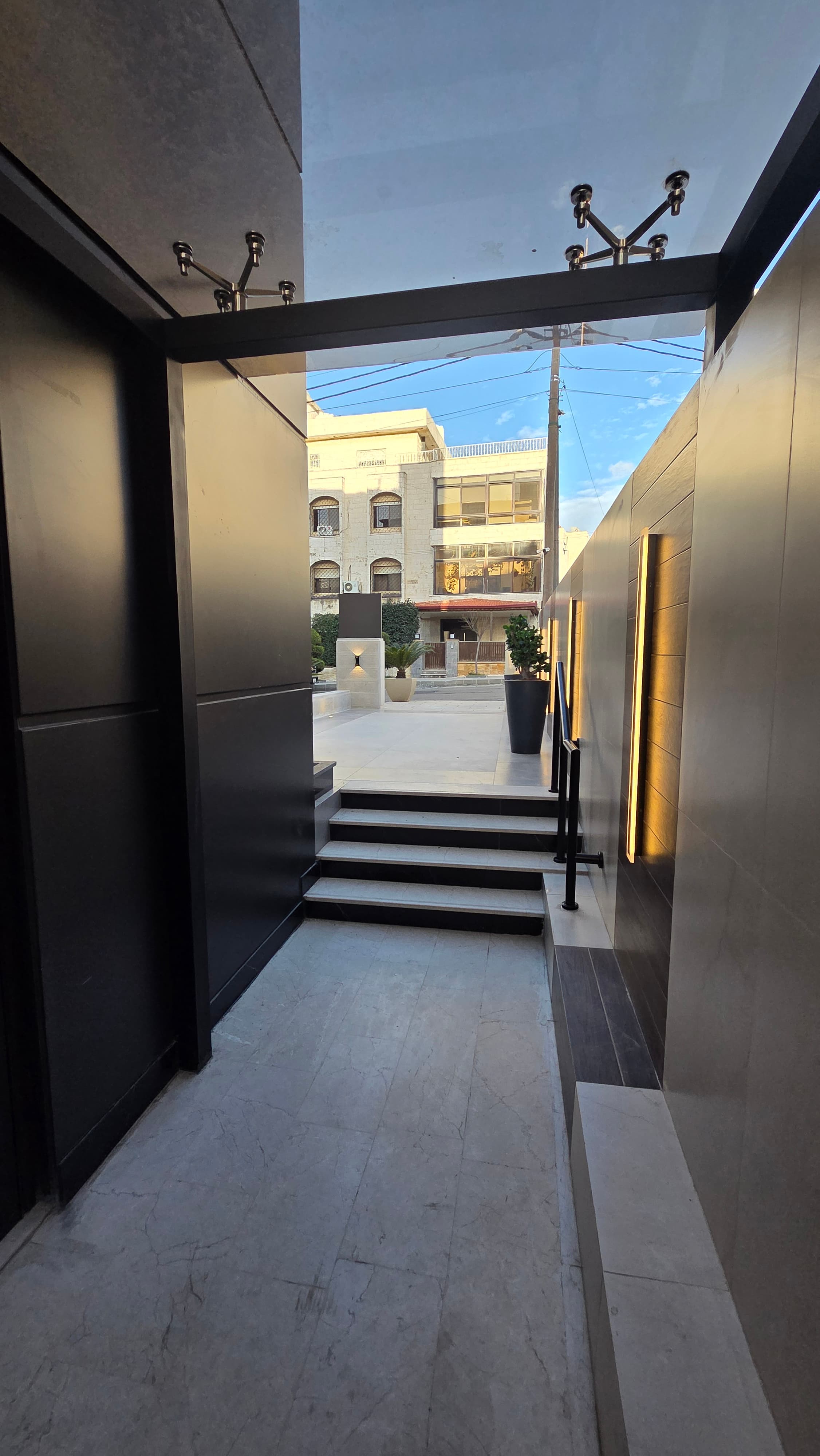 Glass canopy entrance with marble steps and stainless steel fittings